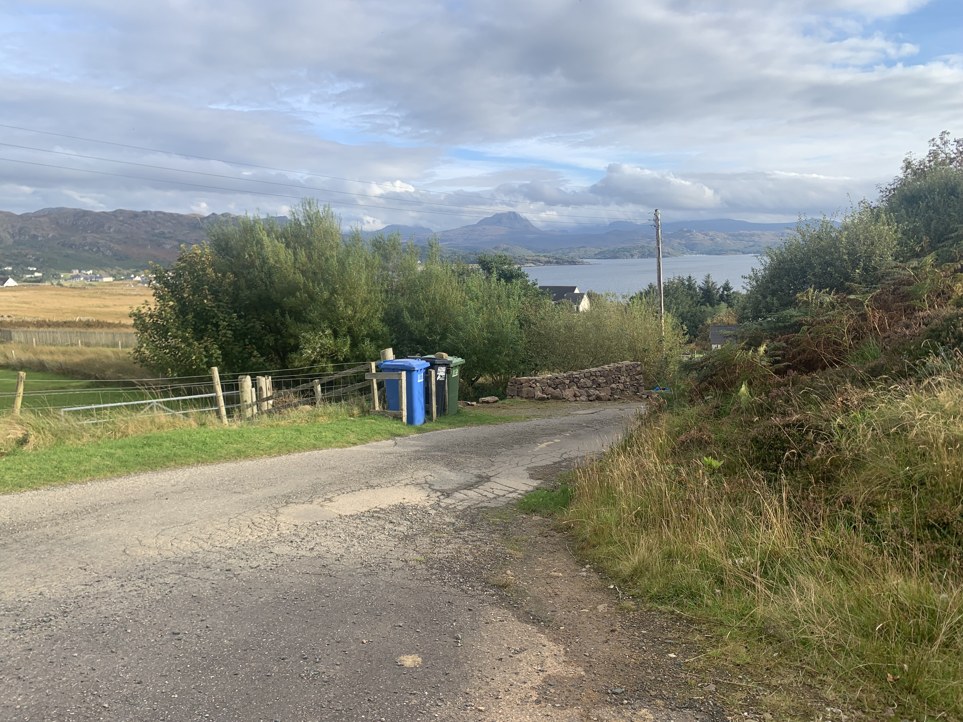 An old wire fence and timber bine store with Gairloch village in the background