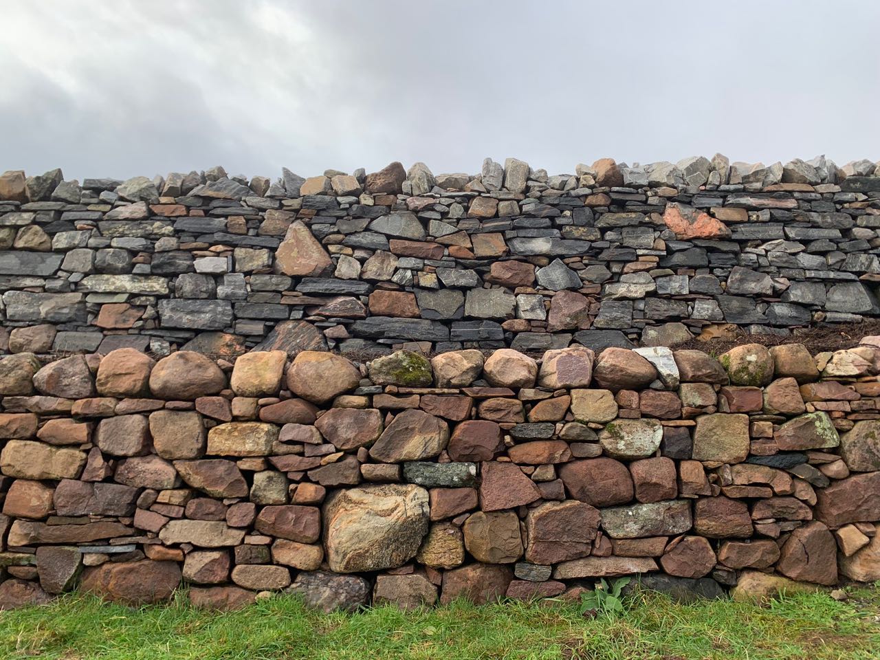 two layers of dry stone wall the top layer mostly gray stone the bottom layer mostly pink